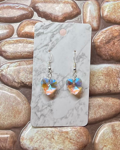 Heart-shaped earrings on a marble card with a stone background