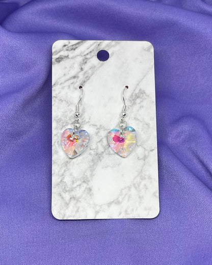 Heart-shaped earrings on a marble card with a purple fabric background