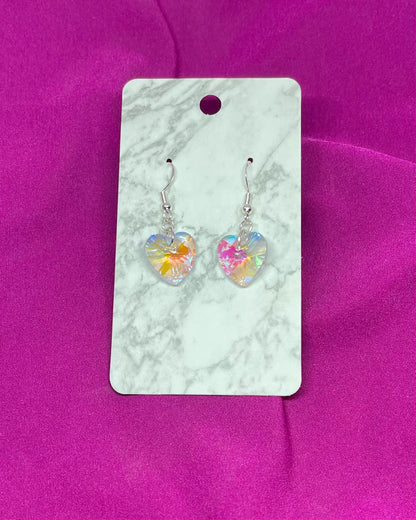 Heart-shaped earrings on a marble card with a pink background