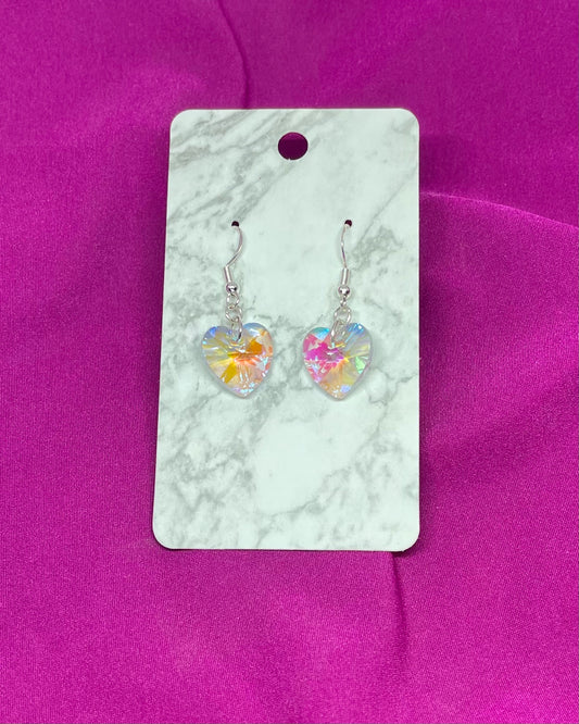 Heart-shaped earrings on a marble card with a pink background