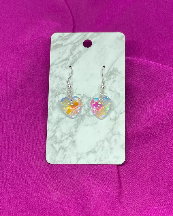 Heart-shaped earrings on a marble card with a pink background