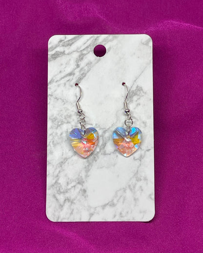 Heart-shaped earrings on a marble card with a pink background
