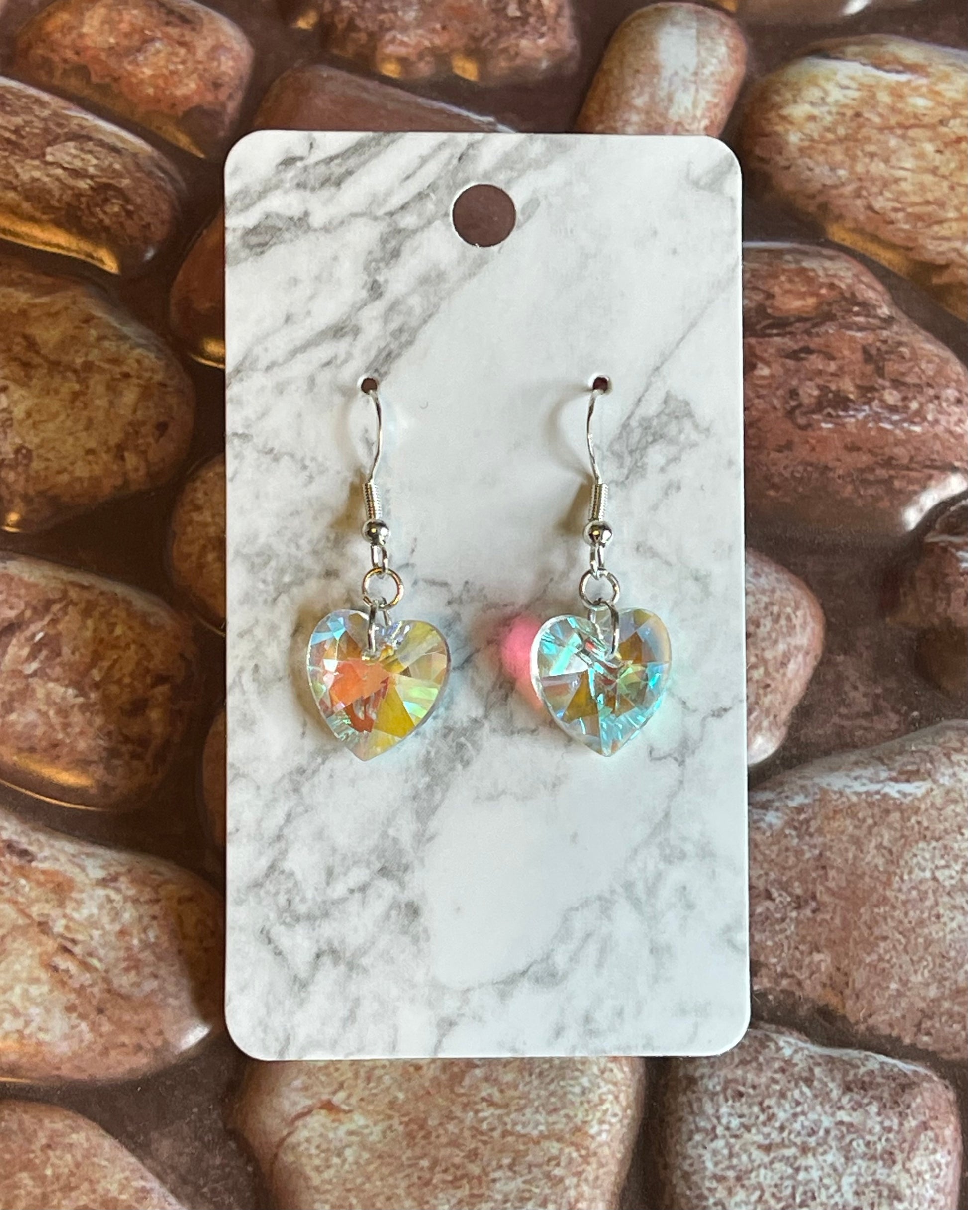 Heart-shaped earrings on a marble card with a stone background
